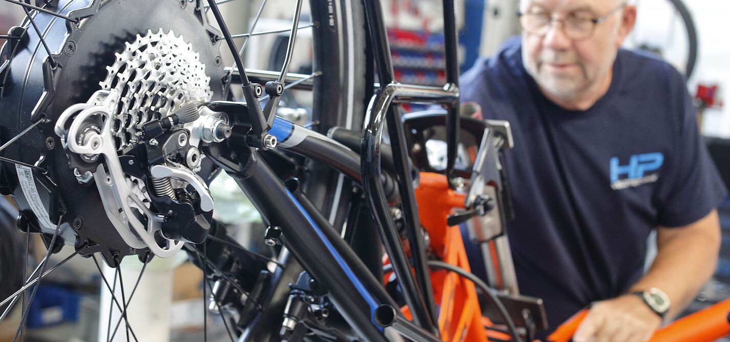 Fahrrad-Nachrüstung in der Werkstatt Ein Fahrradmechaniker arbeitet in seiner Werkstatt an der Nachrüstung eines Elektrofahrrads.